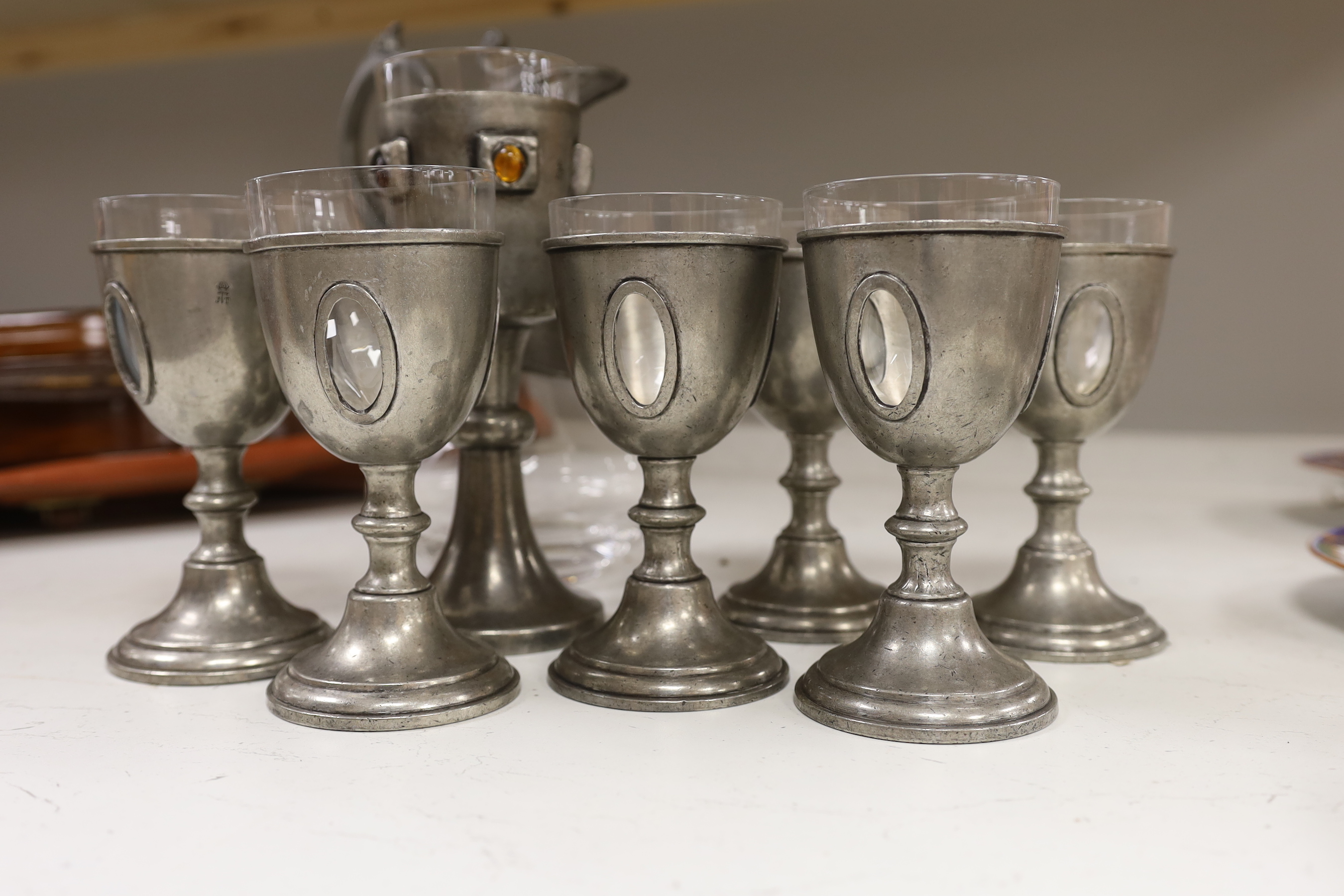 A set of six 20th century French pewter and glass goblets, together with larger example inset with cabochon stones and a pewter mounted glass claret jug, the largest 28cm high